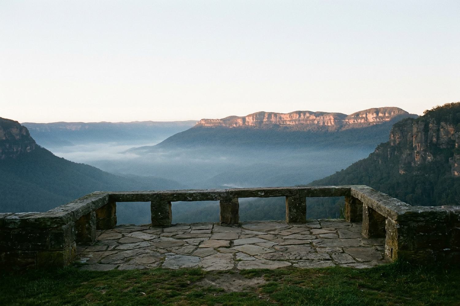 A wide valley at first light with mist in the bottom and sun on the far ridge.