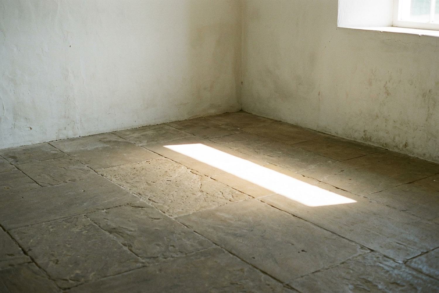 One hard edged bar of low sunlight lying diagonally across a bare stone floor.