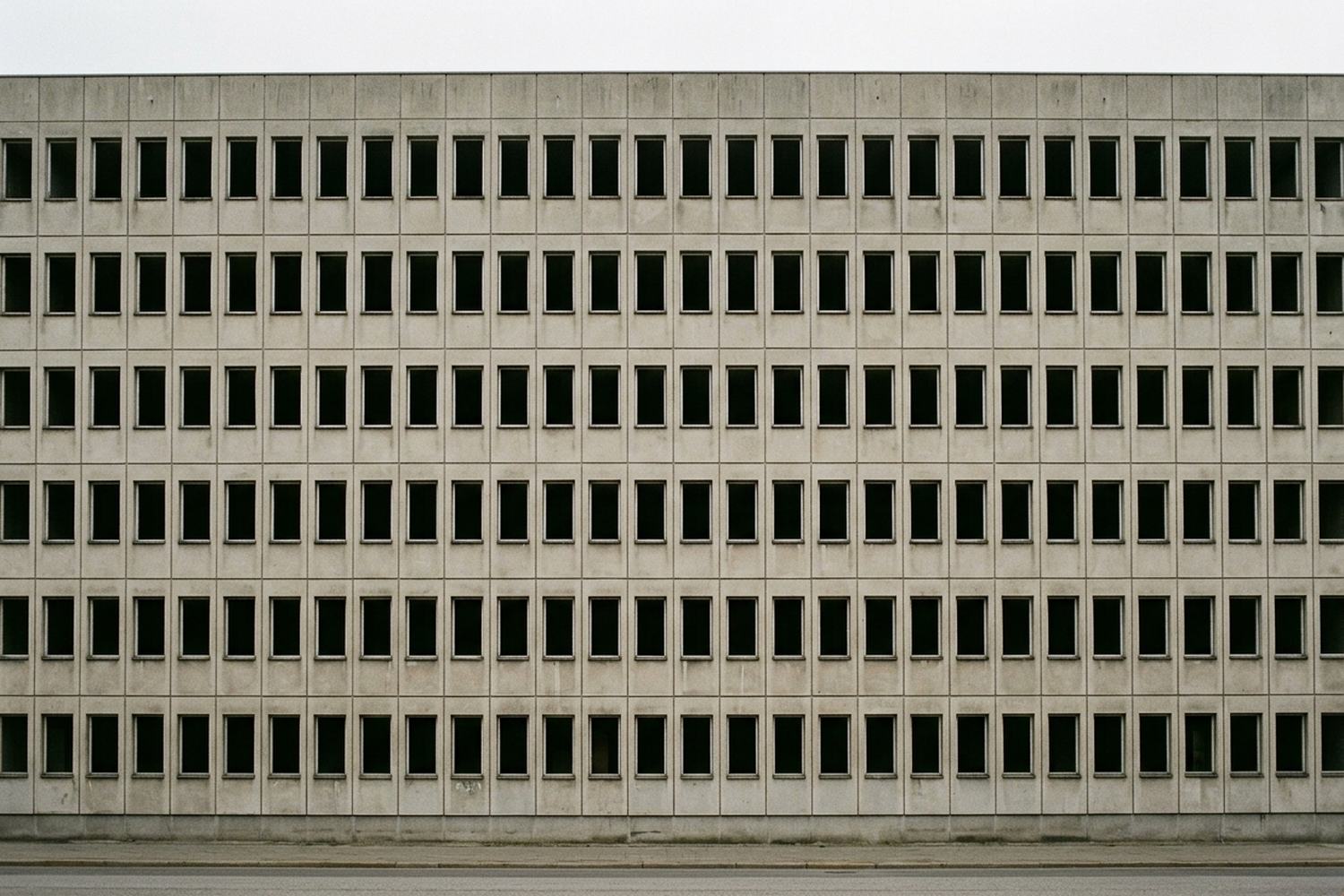 A facade of many small identical windows, every one of them dark and empty.